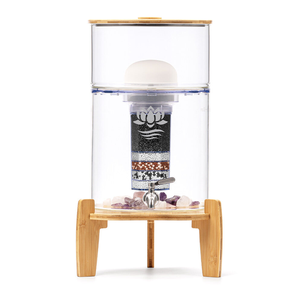 Eleganter Glas-Wasserfilter mit Bambus-Deckel und -Sockel von Lotus Vita, auf einem Bambusgestell stehend. Die Filterkartusche und Edelsteine im Inneren sind sichtbar.