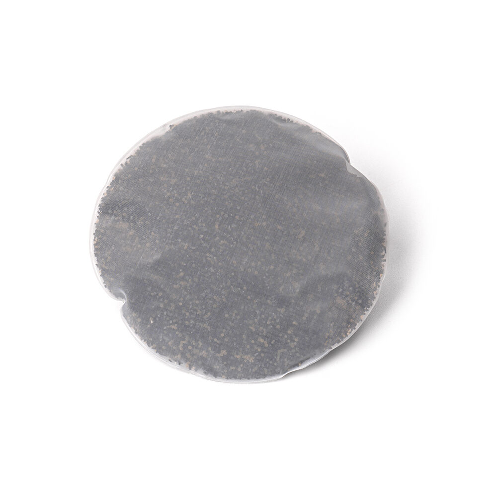 Einzelnes, rundes Filterpad, gefüllt mit Granulat zur Vorfilterung von Kalk in Trinkwasserfiltern von Lotus Vita.