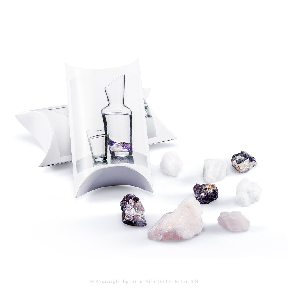 Naturbelassene Kristalle wie Rosenquarz und Amethyst zur Wasserenergetisierung neben ihrer Verpackung.