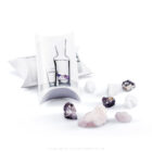 Naturbelassene Kristalle wie Rosenquarz und Amethyst zur Wasserenergetisierung neben ihrer Verpackung.