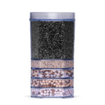 Eine transparente Wasserfilter-Kartusche, die in mehreren Schichten mit verschiedenen Filtergranulaten und Mineralkugeln gefüllt ist.